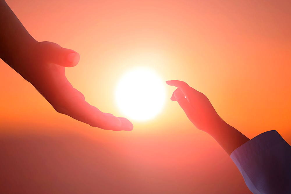 Adult and child hands reaching toward the sun at sunset.